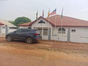 a car parked in front of a building with flags at Kimberly’s Hotel in Tamale