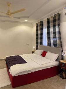 a bedroom with a bed with white sheets and red pillows at Kimberly’s Hotel in Tamale