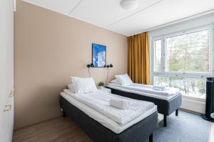 two beds in a room with a window at Hiisi Homes Porvoo Toukovuori in Porvoo