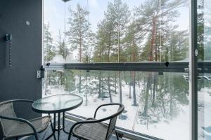 a table and chairs in front of a window with snow at Hiisi Homes Porvoo Toukovuori in Porvoo