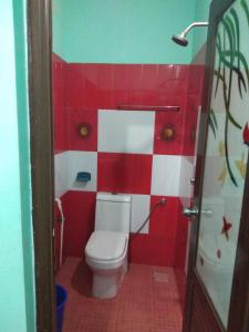 La salle de bains est pourvue de toilettes et de carrelage rouge et blanc. dans l'établissement MN Homestay, à Varkala