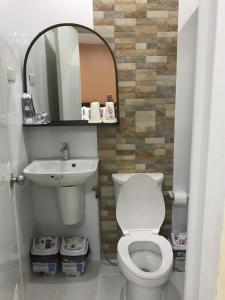 La salle de bains est pourvue de toilettes, d'un lavabo et d'un miroir. dans l'établissement Charos Dormitel, à Dumaguete