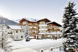 a large building with snow on the ground at Smaragdhotel Tauernblick in Bramberg am Wildkogel