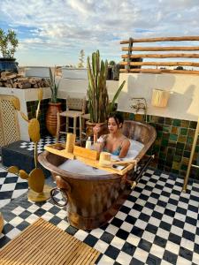 Ein Mann, der in einer Badewanne auf einer Terrasse sitzt in der Unterkunft Le Petit Kenzara & magical rooftop in Marrakesch