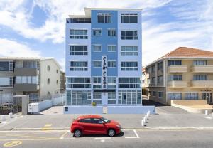 a red car parked in a parking lot in front of a building at Pips Place 301 in Strand