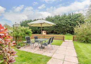 a patio with a table and chairs and an umbrella at Little Broad in Rollesby