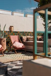 - un canapé et une chaise sur la terrasse dans l'établissement Le Petit Kenzara & magical rooftop, à Marrakech