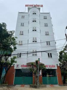 ein hohes weißes Gebäude vor einem Laden in der Unterkunft Thắng Lợi Hotel in Thanh Hóa