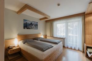 een slaapkamer met een bed en een groot raam bij Parkhotel Matrei in Matrei am Brenner