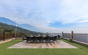 a table and chairs on a deck with a view at Regenta Resort Exotica Dharamshala on Hilltop in Dharamshala