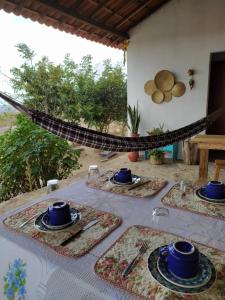 a table with plates of food and a hammock at Chalés Rosados in Serra de São Bento