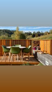 a wooden deck with a table and green chairs at Houten Vakantiewoning "ReisnaarPolen" inclusief royaal ontbijt, sauna en gids in Czarna Góra