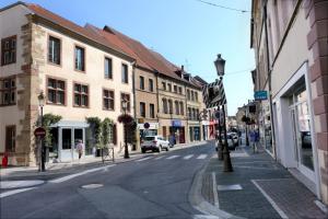 une rue urbaine avec des bâtiments et des voitures sur la route dans l'établissement Petit cocon, à Saint-Avold