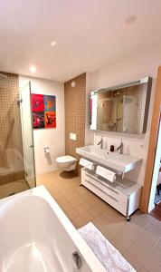 ein Badezimmer mit einer Badewanne, einem Waschbecken und einem WC in der Unterkunft Pineview Waldhaus in Flims