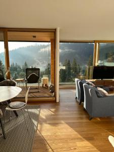 a living room with a table and chairs and a large window at Pineview Waldhaus in Flims
