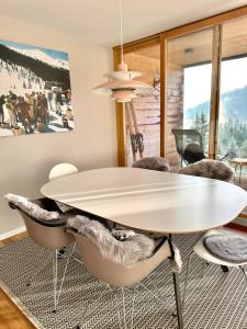 uma sala de jantar com uma mesa branca e cadeiras em Pineview Waldhaus em Flims