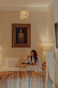 una mujer sentada en una cama en un dormitorio en Le Petit Kenzara & magical rooftop en Marrakech