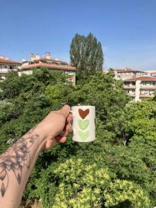 uma mão segurando uma xícara de café com um coração sobre ele em A Peacefull Terrace at the heart of Ankara em Ancara