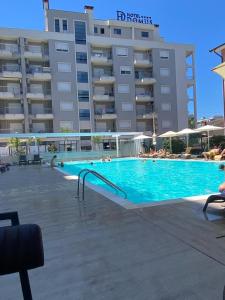 a swimming pool in front of a large building at Domus Hotel & Apartments in Shëngjin