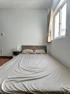 een groot bed in een witte kamer met een raam bij Taibo house 2 in Ho Chi Minh-stad