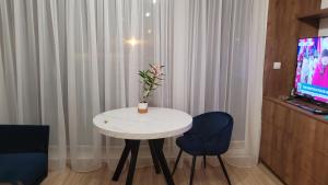 mesa blanca pequeña con 2 sillas y TV en Queen Apartament Centrum z garażem, en Mińsk Mazowiecki