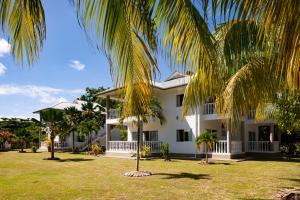 a white house with palm trees in front of it at Casa Tara Villas in Grand'Anse Praslin