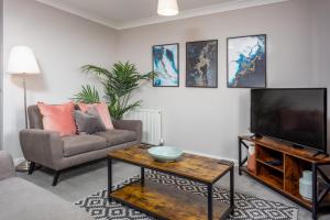 ein Wohnzimmer mit einem Sofa und einem TV in der Unterkunft Bay View - Donnini Apartments in Ayr