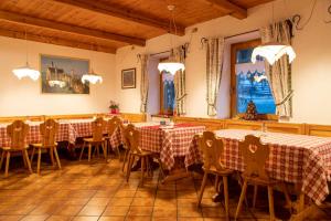 uma sala de jantar com duas mesas e cadeiras com toalha de mesa vermelha e branca em Agritur Iellici em Castello di Fiemme