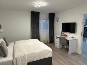 a bedroom with a bed and a desk with a television at The perfect room in Karlsruhe