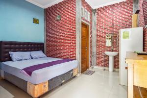 a bed in a room with a brick wall at Joglo Ndalem Sabine Syariah in Piyungan