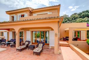 a house with a patio with chairs and tables at Villa Zahara in Alcudia