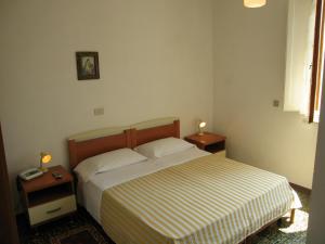 a bedroom with a bed and two night stands with lamps at Albergo Natucci in Montecatini Terme