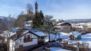 a village in the snow with a clock tower at Agritur B&B Iellici in Castello di Fiemme