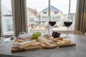 una tabla de cortar de madera con queso y copas de vino en una mesa en BOURNECOAST: STYLISH FLAT WITH SEA GLIMPSES - FM8405, en Southbourne
