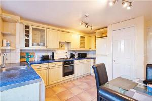 une grande cuisine avec des placards en bois et une table dans l'établissement Manor Place Apartment Thamesmead, à Thamesmead