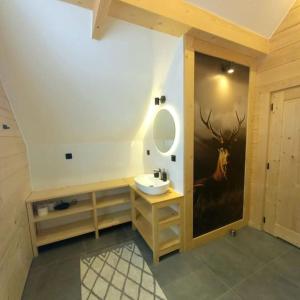 a bathroom with a sink and a deer painting on the wall at Domek z bali Dotyk Motyla in Łapsze Niżne