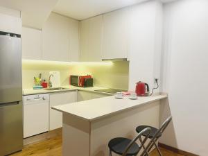 uma cozinha com armários brancos e um balcão com cadeiras em Apartamento Mirador Encamp em Encamp