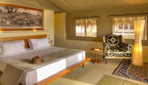 sypialnia z dużym łóżkiem i krzesłem w obiekcie Kudu Safari Camp w mieście Koito