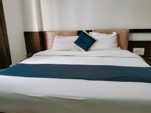 a large bed with blue and white sheets and pillows at Hotel Taj Prince in Agra