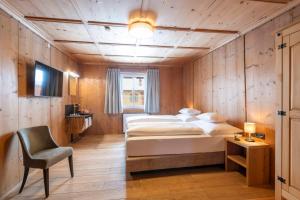 a bedroom with a bed and a chair in a room at NATURPARKGUT - Apartment HOLZGAU1758 in Holzgau