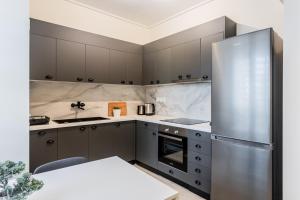 La cuisine est équipée de placards gris et d'un réfrigérateur en acier inoxydable. dans l'établissement Radiant 2BR Apartment in Neo Psichiko by UPSTREET, à Athènes