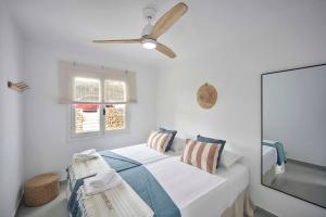 una camera bianca con letto e ventilatore a soffitto di OasisBlanc Binibeca a Binibeca Altre 36 foto