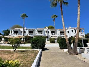 un grande edificio bianco con palme di fronte di OasisBlanc Binibeca a Binibeca