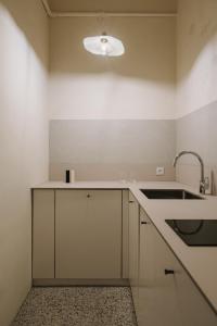 uma cozinha com armários brancos, um lavatório e uma luz em HERE Apartments em Cracóvia
