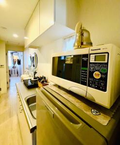 un four micro-ondes installé au-dessus d'un comptoir de cuisine dans l'établissement YUYUSO Hostel, à Tokyo