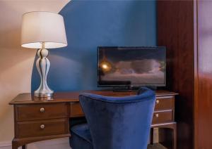 a room with a desk with a lamp and a tv at Cranmere Lichfield in Lichfield