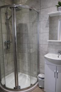 a shower with a glass door next to a sink at Cranmere Lichfield in Lichfield