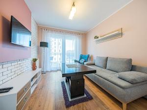 a living room with a couch and a table at Hello Apartments 4 Oceany z prywatnym parkingiem in Gdańsk