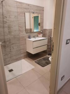 uma casa de banho com um lavatório, um espelho e um chuveiro em Appartamento Suite Antiche Terme - Zero Barriere em Acqui Terme