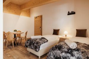 two beds in a room with a table and chairs at Hotel Monte Cherz in Arabba +53 photos